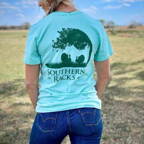 the back of a mint green t-shirt with a dark green screen printed circular silhouette of tree branches and two long beard gobblers with Southern Racks printed underneath the image